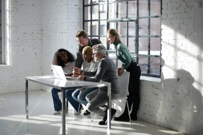 collaboration teamwork group team gathered around laptop