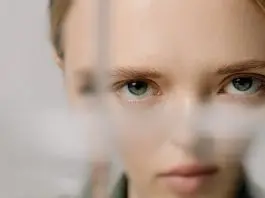 woman with face distorted as looking partially through glass