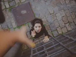 lady reaching up to hand of someone else helping her