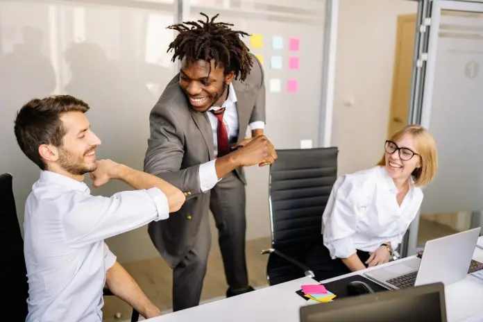 3 office workers, 2 of them elbow bumping greeting