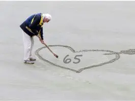 retired man writing 65 in sand on beach