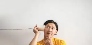man in yellow t shirt listening into cup on string