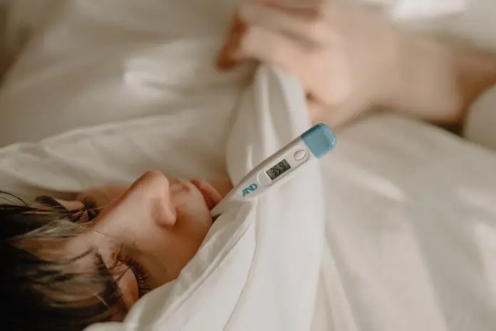 pexels-cottonbro-4114018 man under duvet with thermometer in mouth