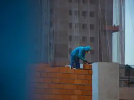 builder laying bricks on wall
