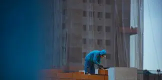 builder laying bricks on wall