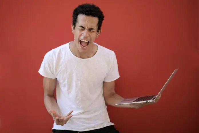 pexels-andrea-piacquadio-3799830 man holding laptop showing frustration