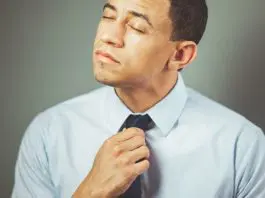 man adjusting tie looking uncomfortable
