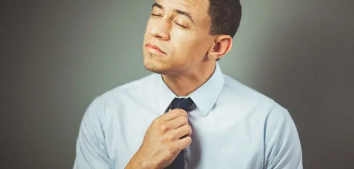 pexels-craig-adderley-1605226 man adjusting tie looking uncomfortable