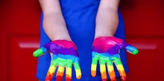 person with rainbow paint on hands