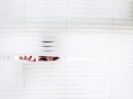 man peeking through venetian blind