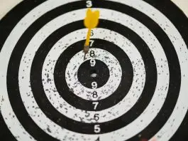 black and white dartboard with dart missing bullseye