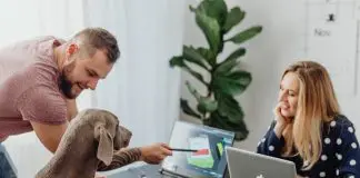 man pointing out info on a laptop to a dog as woman looks on