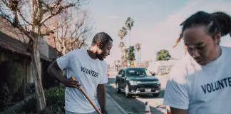 two men sweeping outside with "volunteer" t-shirts on