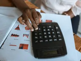 person using calculator over sheet of data