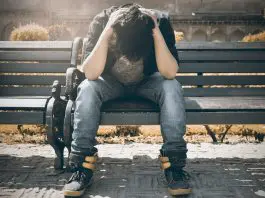 man sitting on bench with his head in his hands