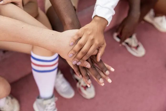 pexels-monstera-5384623 team with hands on top of each others in team huddle