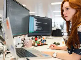 busy woman at desk with 3 monitors