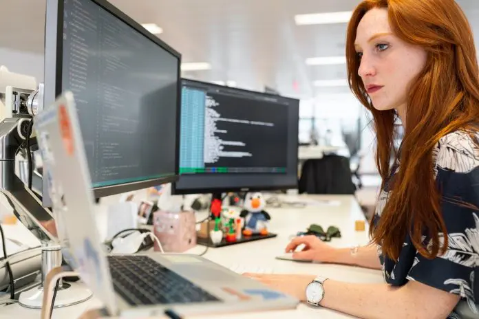 busy woman at desk with 3 monitors