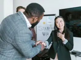 man shaking womans hand thanking her with colleague looking on
