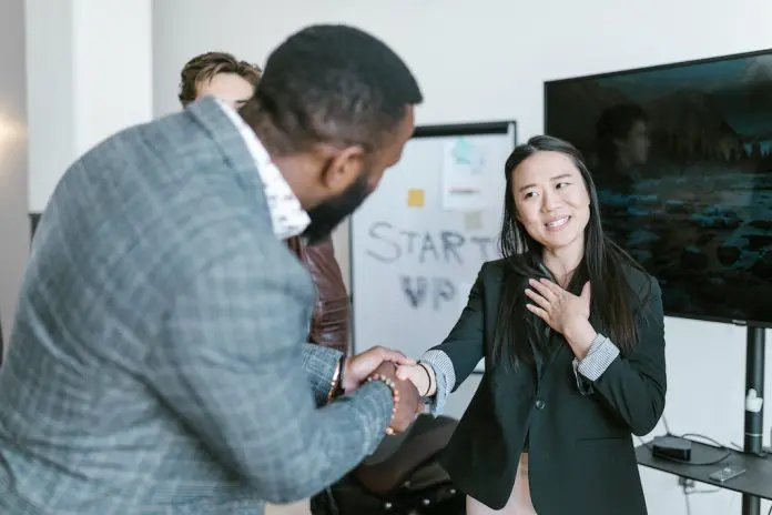 pexels-rodnae-productions-7413983 man shaking womans hand thanking her with colleague looking on