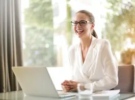 lady in white shirt sitting at laptop, smiling widely