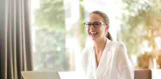 lady in white shirt sitting at laptop, smiling widely