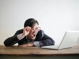 Yelling man in ssuit looking at laptop