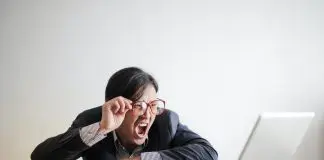 Yelling man in ssuit looking at laptop