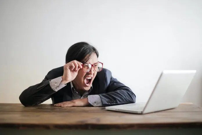 Yelling man in ssuit looking at laptop