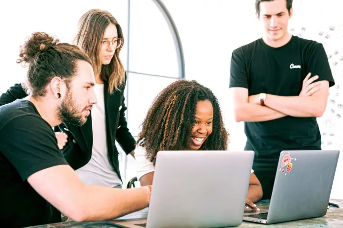 pexels-canva-studio-3153207 A Group of smiling Professionals huddled around laptops Sharing Ideas