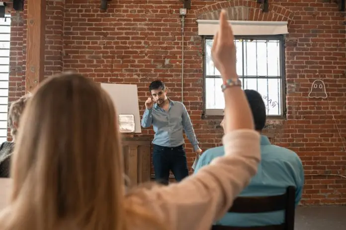 pexels-rodnae-productions-5756655 lady with raised hand to ask a question of lecturer/presenter