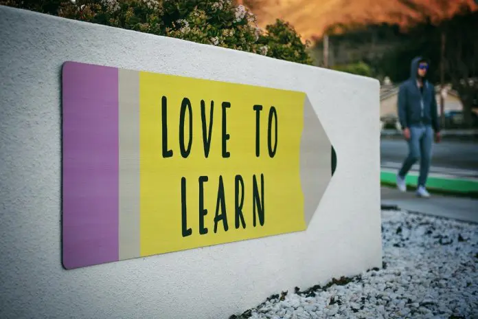 man walking past building that has sign that says "love to learn"