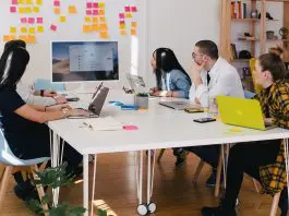 group of professionals in an office reviewing business results on a large monitor