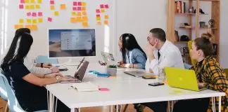 group of professionals in an office reviewing business results on a large monitor