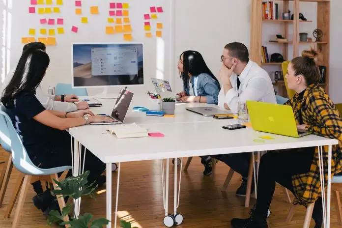 jason-goodman-vbxyFxlgpjM-unsplash group of professionals in an office reviewing business results on a large monitor