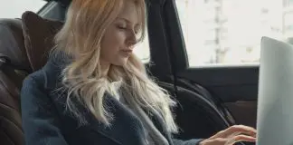 businesswoman in back of car on laptop