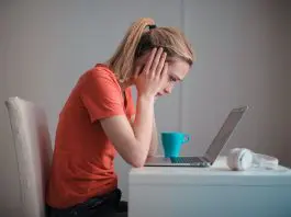 lady with head in her hands staring blankly at laptop