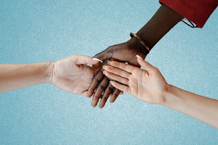 Intertwined hands of people of different color and race
