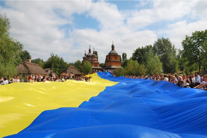 gropu of people holding huge Ukrainian flag