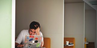 man with head in hands at laptop looking stressed