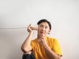 man in yellow t shirt listening into cup on string