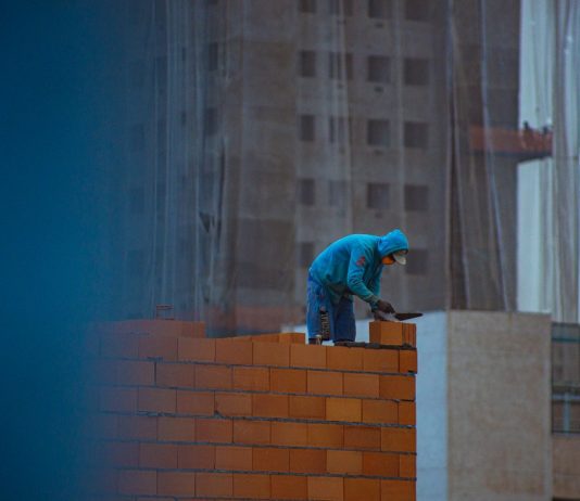 builder laying bricks on wall
