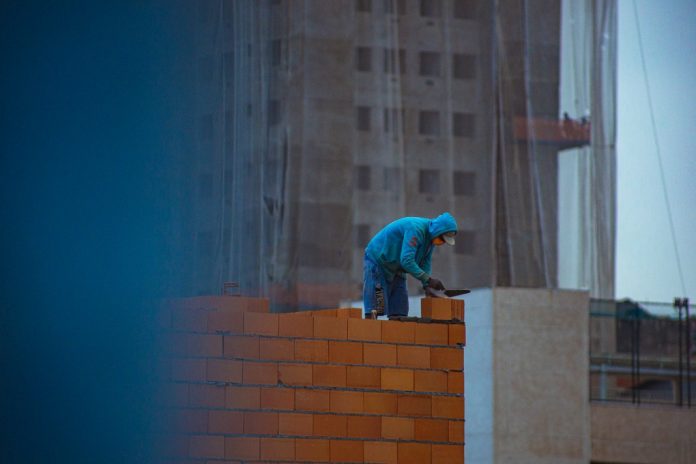 builder laying bricks on wall