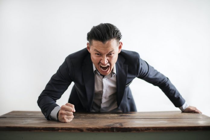 aggressive man stomping fist on desk