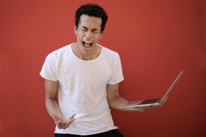 man holding laptop showing frustration