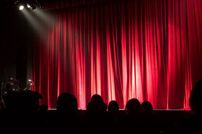 lights shining on empty stage with large red curtains