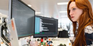 busy woman at desk with 3 monitors