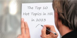 man writing on paper "the top 10 hot topics in HR in 2023"