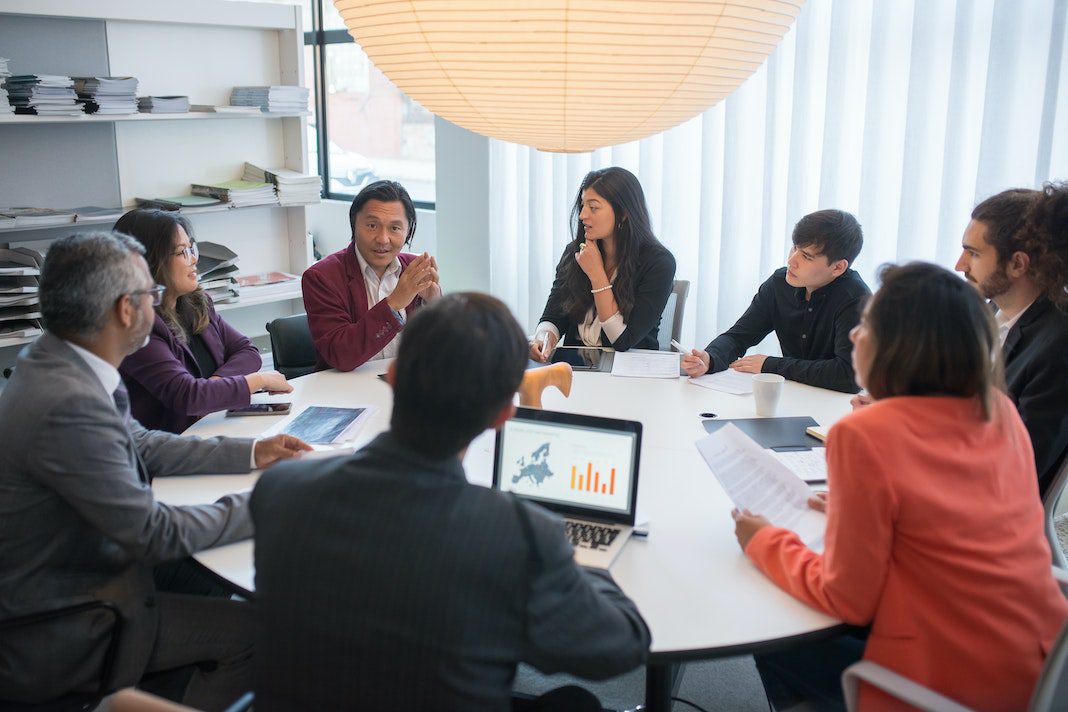 group in deep discussion around round conference table